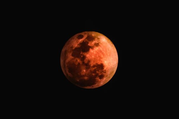 Una luna llena brillante iluminando un paisaje misterioso, sugiriendo una conexión con lo paranormal.
