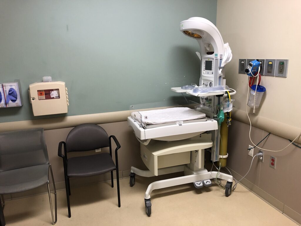 Cama de reanimación con monitor encendido y cortina corrida en una sala de hospital