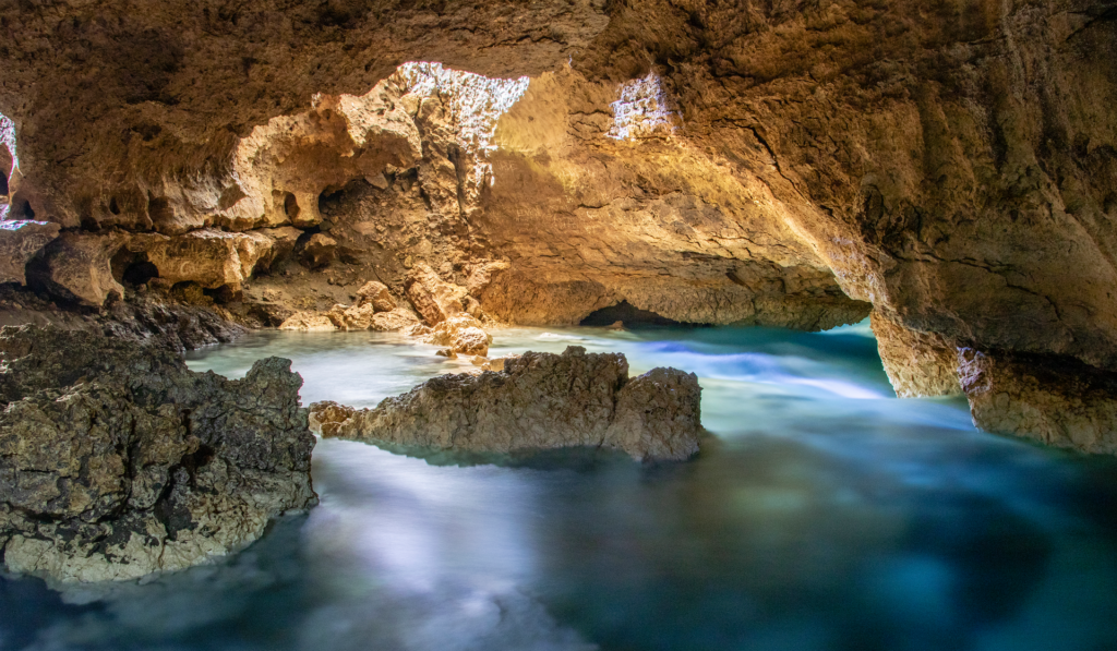 Estalactitas colgando del techo de una cueva sumergida iluminadas por el foco de un buceador
