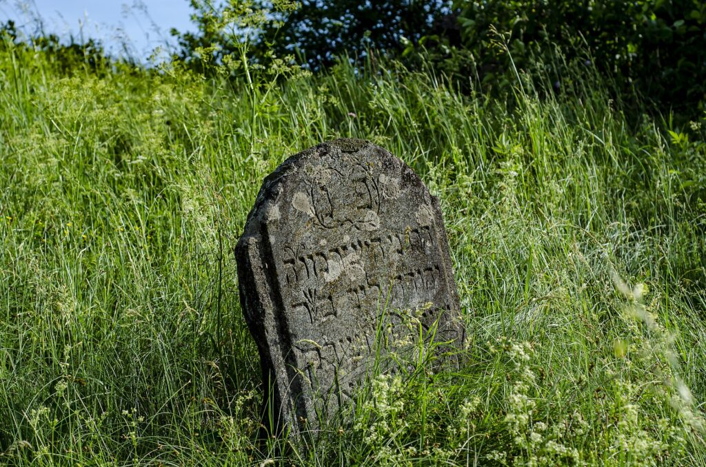 L&aacute;pida antigua de piedra cubierta de l&iacute;quenes en un cementerio rural al atardecer