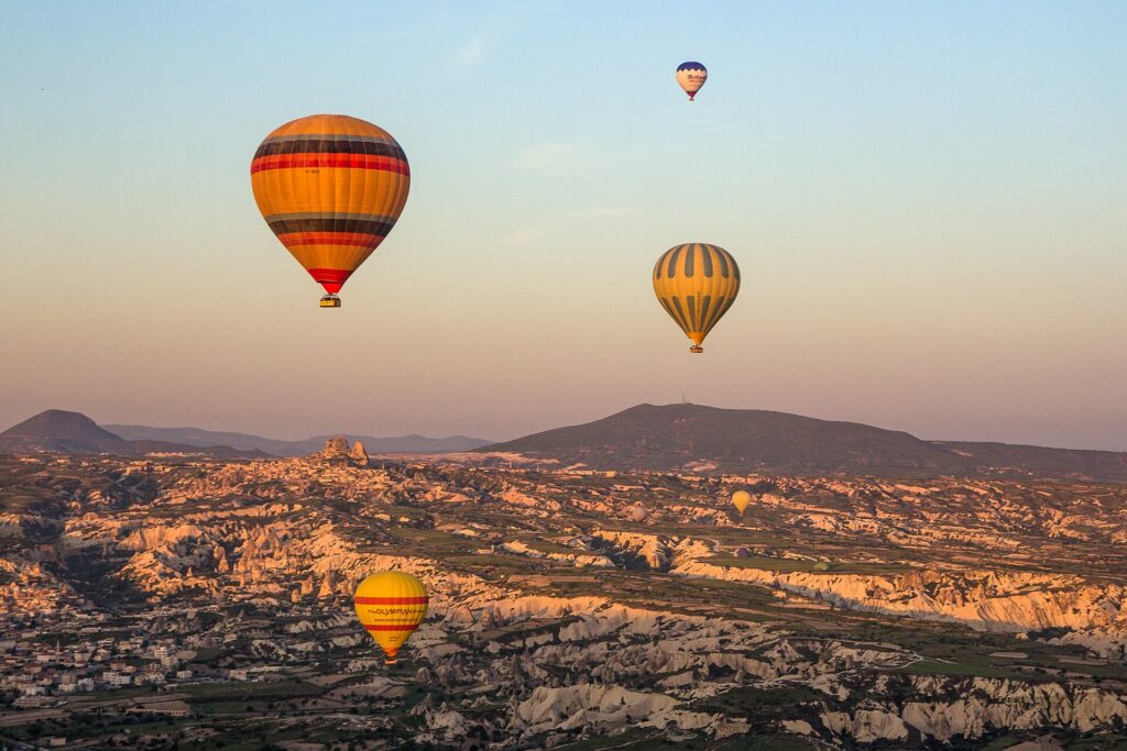 Globo aerostático de colores en vuelo bajo sobre un campo abierto al amanecer