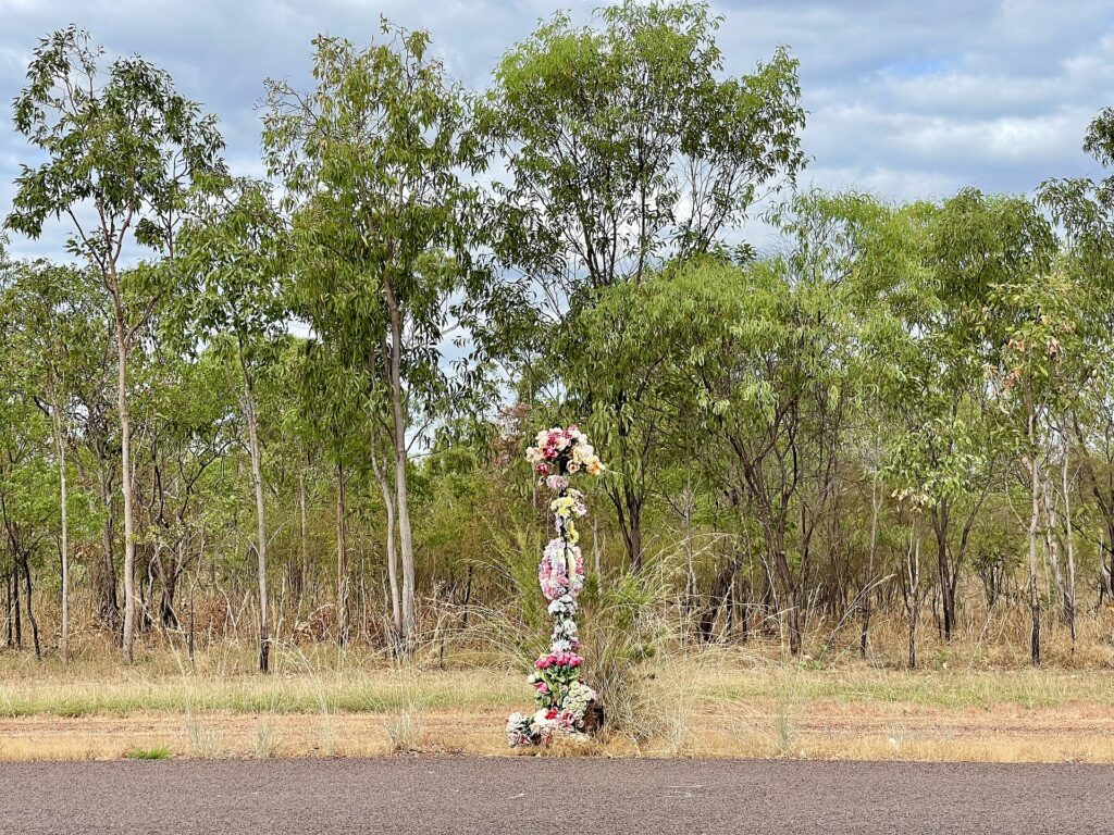Cruz de madera con flores secas clavada en el arc&eacute;n de una curva de monta&ntilde;a