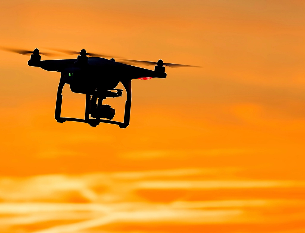 Dron de cuatro hélices suspendido en el aire con el cielo despejado al fondo