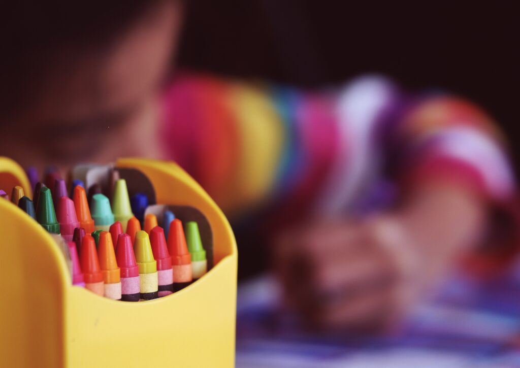 Dibujo infantil hecho con ceras sobre papel blanco con figuras y un animal