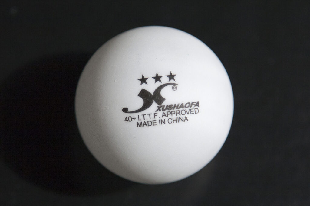 Varias pelotas blancas de tenis de mesa agrupadas sobre una superficie clara y lisa