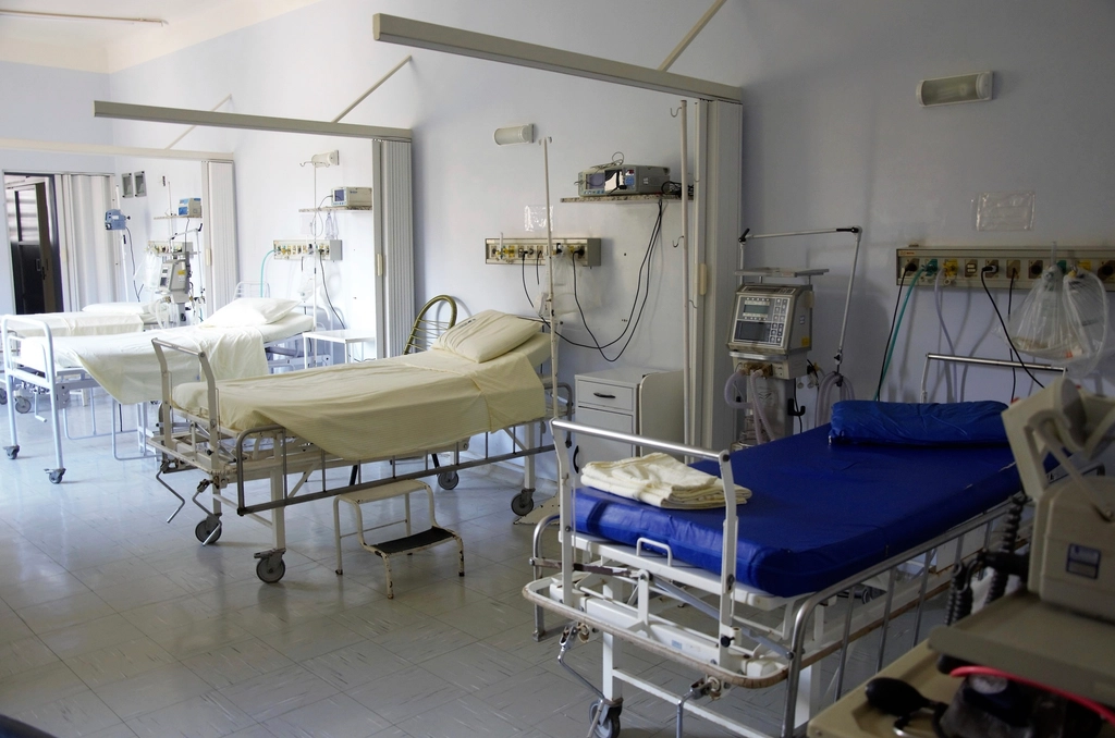 Cama de hospital con monitor de constantes vitales encendido en una habitación en penumbra